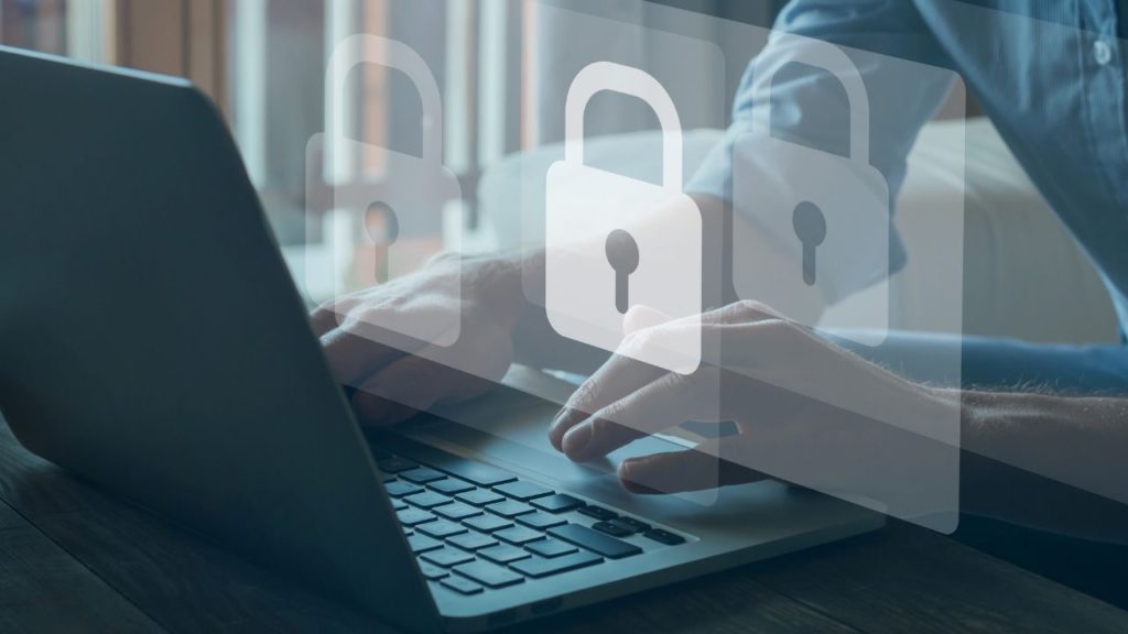 Mãos digitando em um laptop com ícones de cadeado flutuantes, representando a segurança e o conceito de zero trust na navegação online.