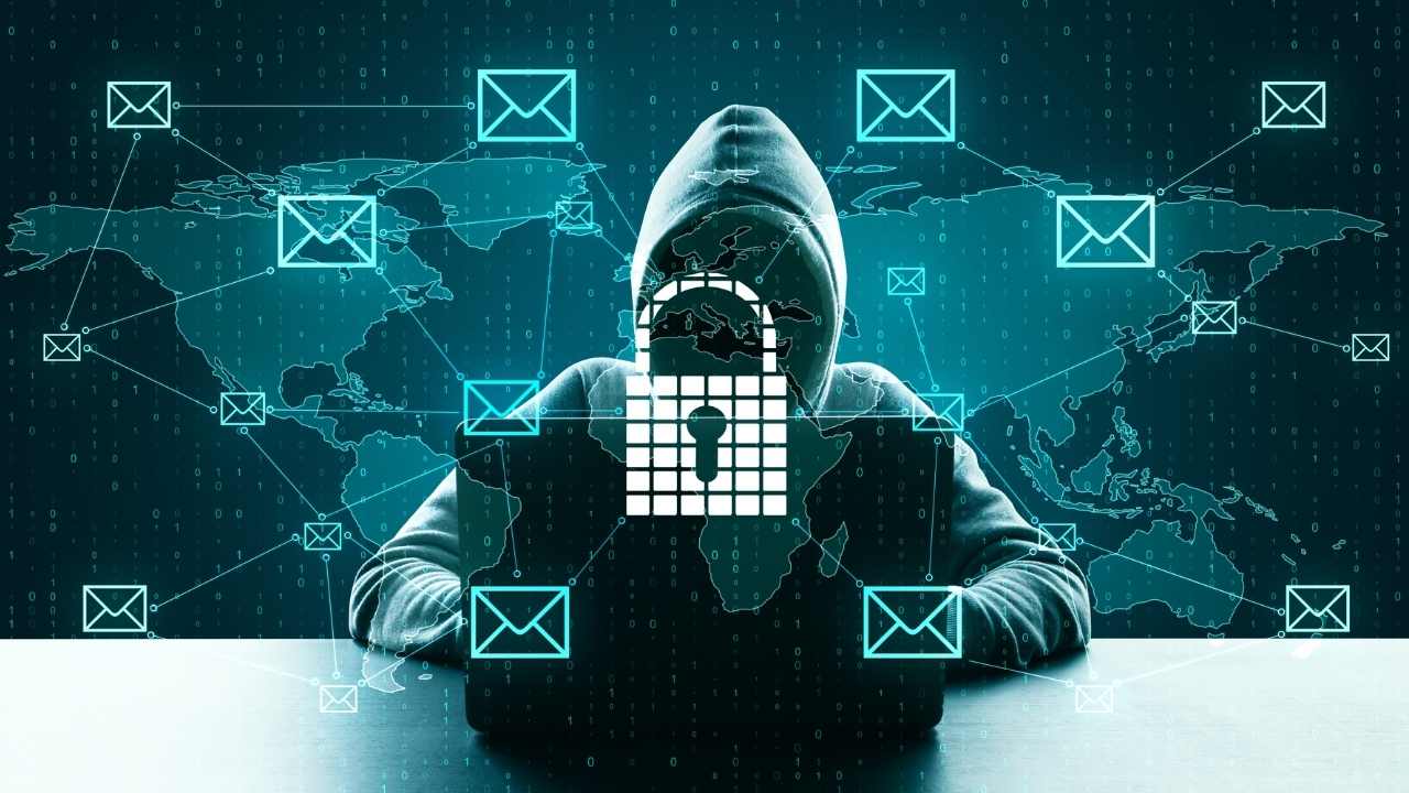 Pessoa com capuz operando múltiplos computadores em ambiente escuro e tecnológico, simbolizando um ataque de phishing em andamento com códigos binários e imagens digitais nas telas.