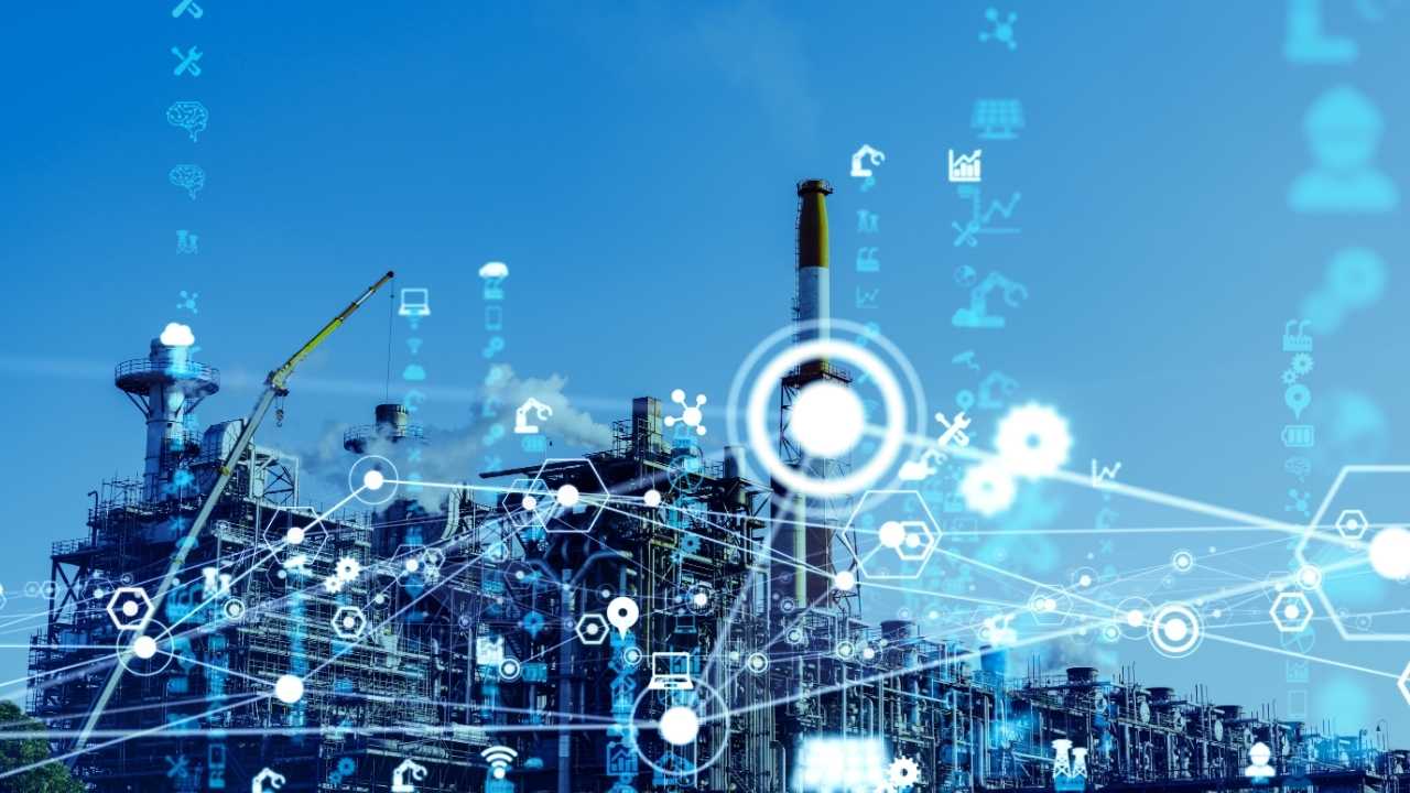 Imagem de uma fábrica com chaminés e máquinas, cercada por uma rede de ícones digitais e hexágonos que representam a conexão e a tecnologia, sugerindo um dispositivo IoT em um contexto de solução industrial.