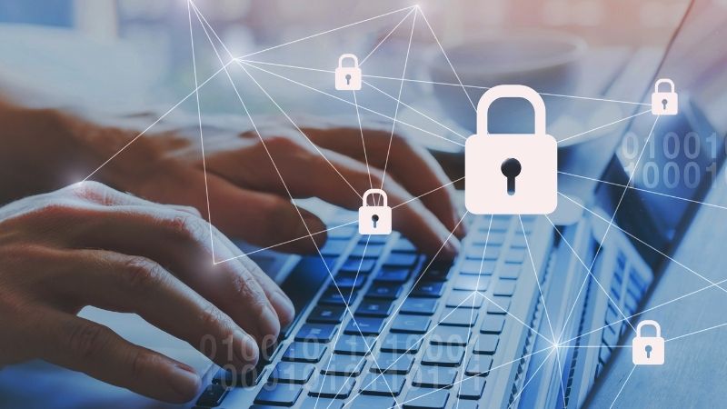 Mãos digitando em um notebook com ícones de cadeados e conexões digitais, simbolizando a proteção contra vazamento de dados na internet.